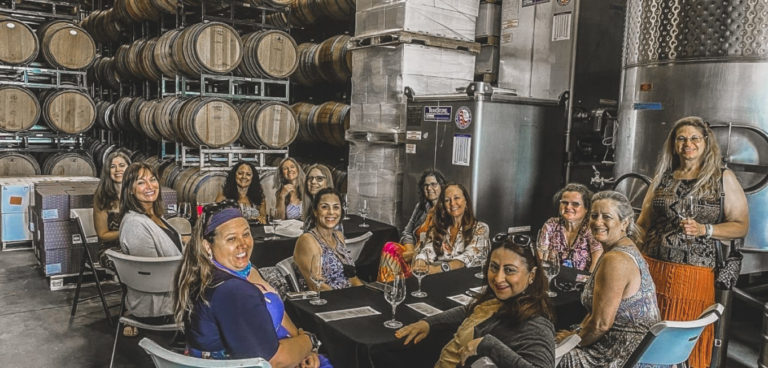 group of girls on a wine trip in a wine cellar with barrels