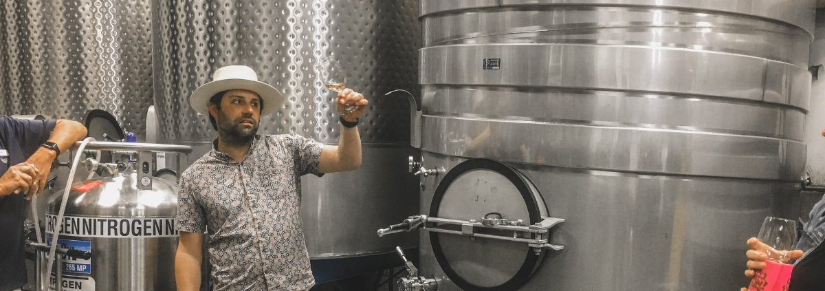 a man holding up a glass of red wine in a winery while on a Paso wine tours