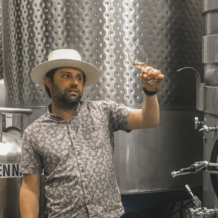 a man holding up a glass of red wine in a winery while on a Paso wine tours