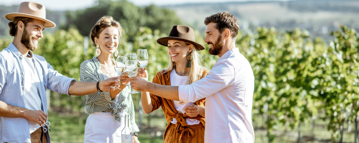 a group of friends that went wine tasting together cheersing in a vineyard