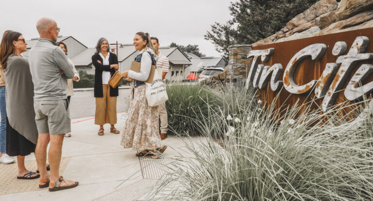 walking tour group made up of 6 people and the tour guide standing in front of the tin city sign