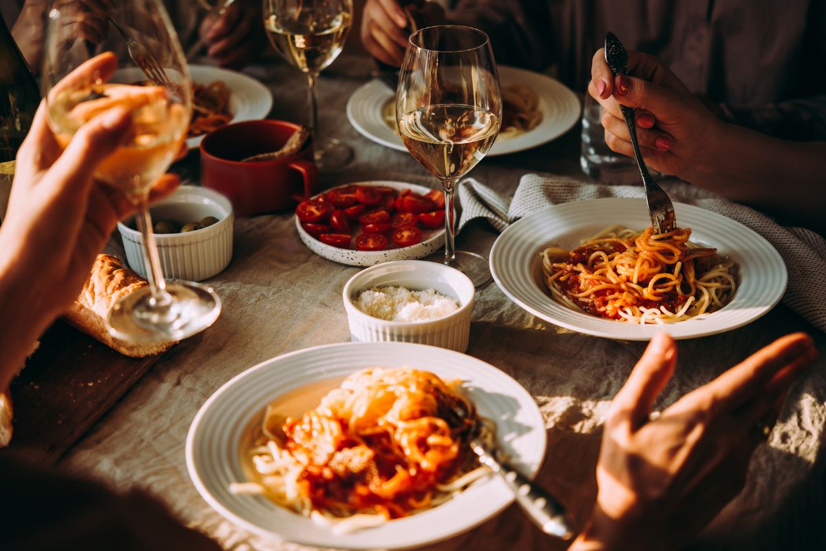 pasta and wine dish being enjoyed by a group of people