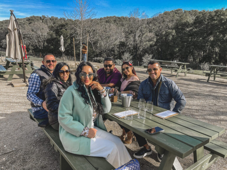 3 women and 3 men sitting at a picnic bench in a park under a blue sky in winter in Paso Robles, CA