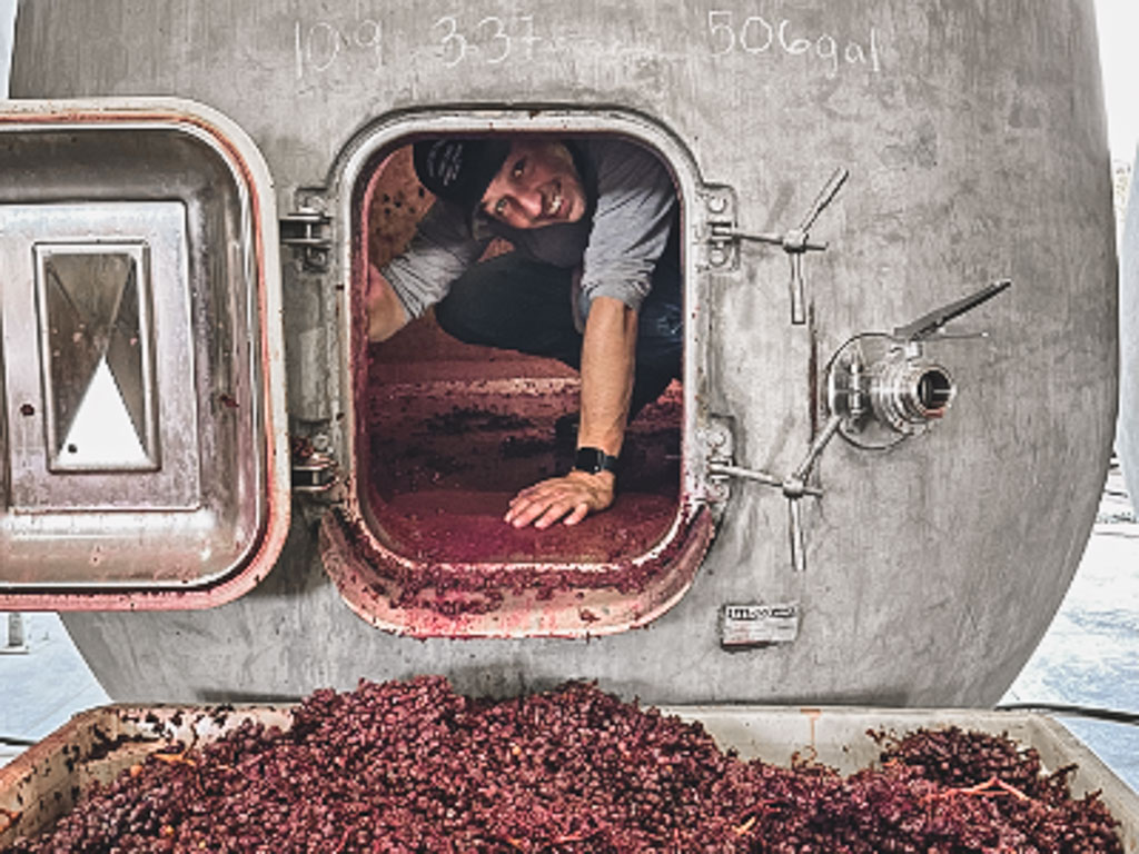 Wine maker in concrete fermenting cleaning the lees